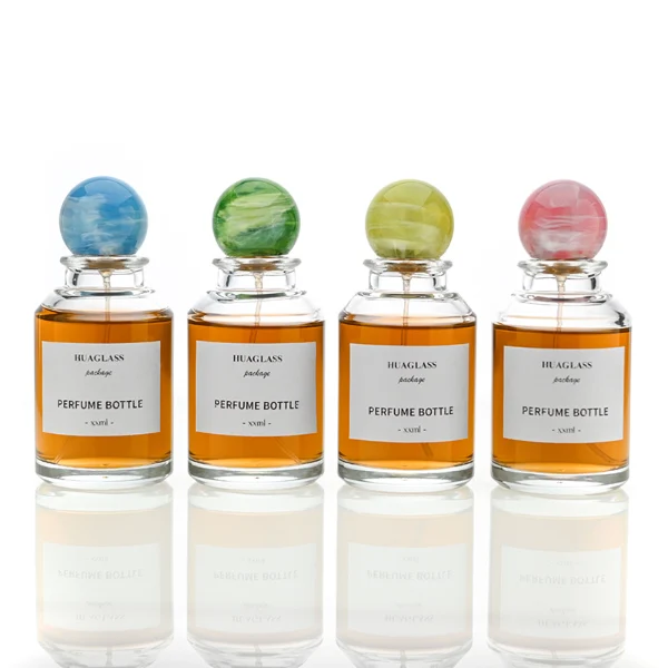 HUA0017 perfume bottle, heavy-base cylindrical round glass bottle with clear finish, featuring a square paper label and a large spherical plastic ball cap showcasing unique marbled veining patterns, elegant classic fragrance packaging design in 100ml