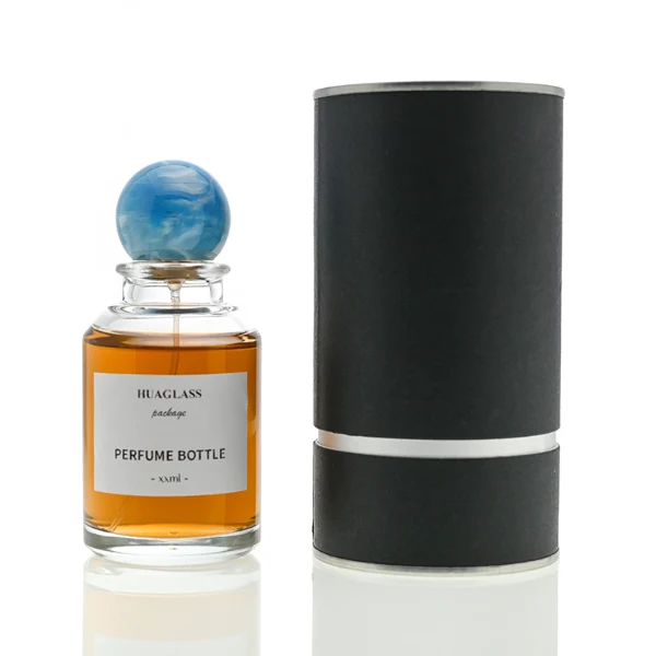HUA0017 perfume bottle, heavy-base cylindrical round glass bottle with clear finish, featuring a square paper label and a large spherical plastic ball cap showcasing unique marbled veining patterns, elegant classic fragrance packaging design in 100ml