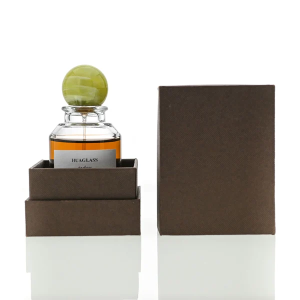 HUA0017 perfume bottle, heavy-base cylindrical round glass bottle with clear finish, featuring a square paper label and a large spherical plastic ball cap showcasing unique marbled veining patterns, elegant classic fragrance packaging design in 100ml