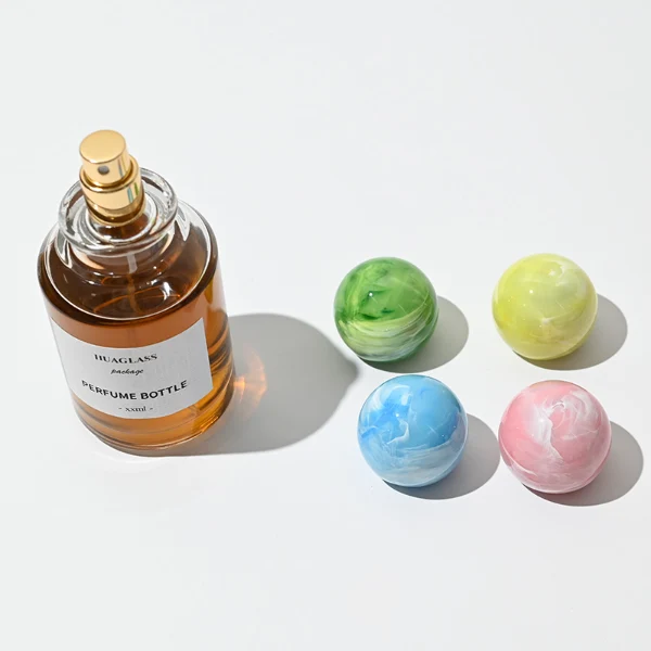 HUA0017 perfume bottle, heavy-base cylindrical round glass bottle with clear finish, featuring a square paper label and a large spherical plastic ball cap showcasing unique marbled veining patterns, elegant classic fragrance packaging design in 100ml