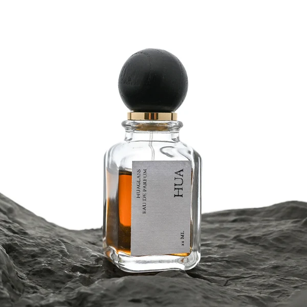 Smooth spherical wooden caps featuring distinct grain finishes in black, dark brown, and natural tones. Elegant square perfume bottles with rounded vertical edges crafted from clear glass filled with golden-amber liquid.