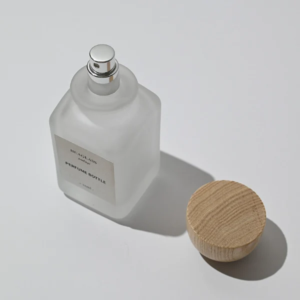 HUA0041 perfume bottle, frosted clear or smoky grey gradient cylindrical round glass bottle featuring an eye-catching inverted conical cup-shaped wood cap with prominent natural wood grain lines, elegant modern fragrance packaging design available in 30ml, 50ml, and 100ml