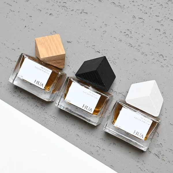Modern cube-shaped caps featuring a glossy black finish.Sleek rectangular perfume bottles crafted from heavy-base clear glass filled with golden-amber liquid.