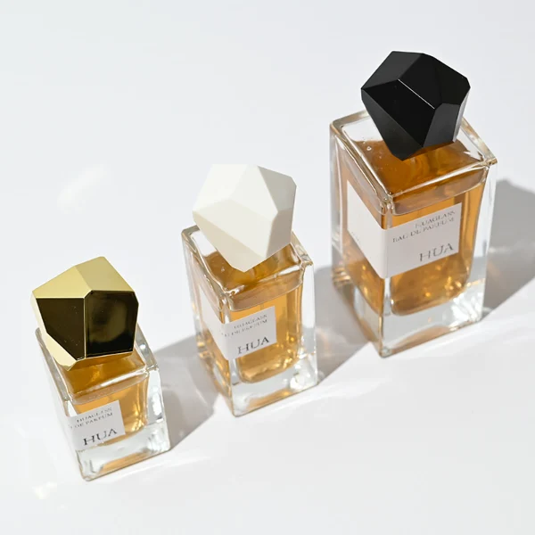 HUA0019 perfume bottle, heavy-base square cuboid glass bottle with clear finish, featuring a rectangular paper label and an eye-catching irregular multi-faceted rock-shaped plastic cap with a high-gloss white finish, elegant modern fragrance packaging design available in 30ml, 50ml, and 100ml