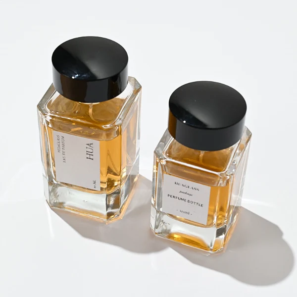 HUA0027 perfume bottle, heavy-base rectangular cuboid glass bottle with clear finish, featuring a square paper label, a polished gold neck, and a wide cylindrical plastic cap with a smooth high-gloss shiny black finish, elegant modern fragrance packaging design available in 30ml, 50ml, and 100ml