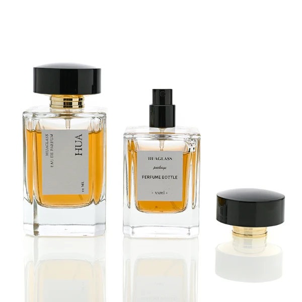 HUA0027 perfume bottle, heavy-base rectangular cuboid glass bottle with clear finish, featuring a square paper label, a polished gold neck, and a wide cylindrical plastic cap with a smooth high-gloss shiny black finish, elegant modern fragrance packaging design available in 30ml, 50ml, and 100ml