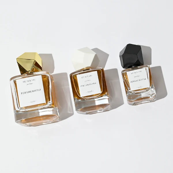 HUA0022 perfume bottle, heavy-base square cuboid glass bottle with clear finish, featuring a square paper label and an eye-catching irregular multi-faceted rock-shaped plastic cap with a high-gloss shiny finish and sharp geometric angles, elegant modern fragrance packaging design in 40ml