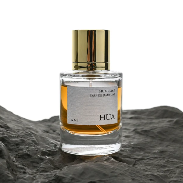 HUA0045 perfume bottle, heavy-base cylindrical round glass bottle with clear finish, featuring a square paper label, a coordinating collar neck accent, and a tall cylindrical aluminum cap with a smooth polished metallic finish, elegant modern fragrance packaging design available in 30ml, 50ml, and 100ml