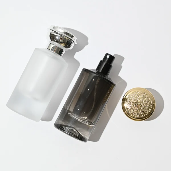 HUA0060 perfume bottle, heavy-base cylindrical round glass bottle with clear finish, featuring a matching neck and an ornate sculptural tiered crown plastic cap with a smooth high-gloss shiny finish, elegant modern fragrance packaging design available in 30ml, 50ml, and 100ml