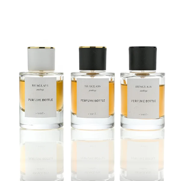 HUA0037 perfume bottle, heavy-base cylindrical round glass bottle with clear finish, featuring a square paper label, a metallic gold collar neck accent, and a short cylindrical plastic cap with a smooth high-gloss shiny finish, elegant modern fragrance packaging design available in 30ml, 50ml, and 100ml