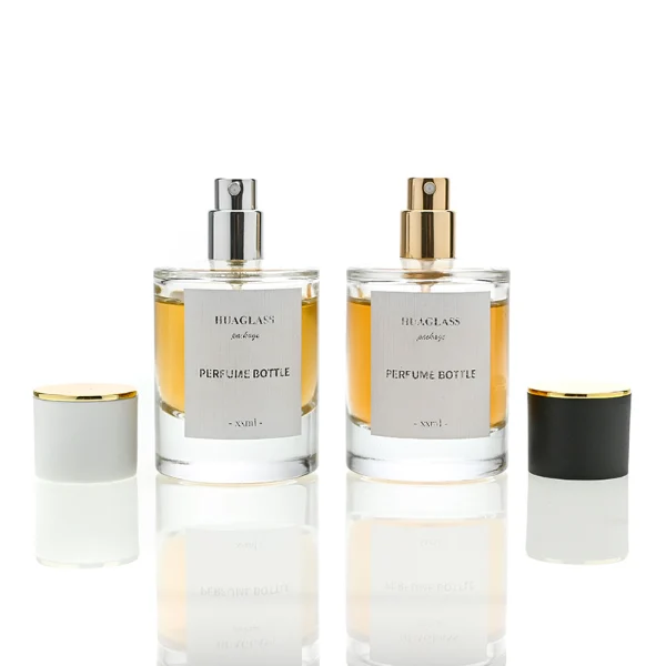 HUA0037 perfume bottle, heavy-base cylindrical round glass bottle with clear finish, featuring a square paper label, a metallic gold collar neck accent, and a short cylindrical plastic cap with a smooth high-gloss shiny finish, elegant modern fragrance packaging design available in 30ml, 50ml, and 100ml