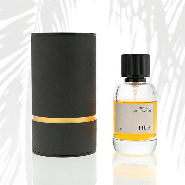 HUA0055 perfume bottle, heavy-base cylindrical round glass bottle with clear finish, featuring a square paper label, a matching neck, and a tall vertically ribbed cylindrical aluminum cap with a smooth polished finish, elegant modern fragrance packaging design available in 30ml, 50ml, and 100ml
