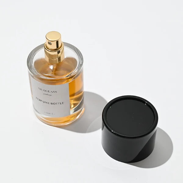 HUA0021 perfume bottle, heavy-base cylindrical round glass bottle with clear finish, featuring a square paper label, a matching neck, and a tall cylindrical plastic cap with a smooth high-gloss shiny finish, elegant modern fragrance packaging design available in 30ml, 50ml, and 100ml