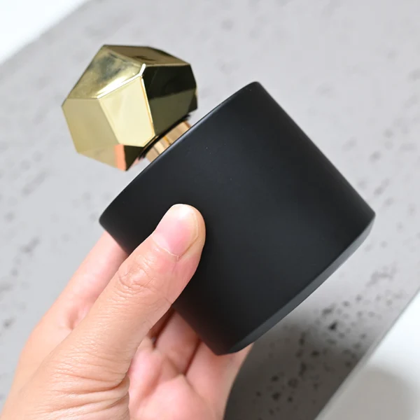 HUA0039 perfume bottle, heavy-base solid high-gloss opaque black cylindrical round glass bottle featuring a prominent asymmetrical multi-faceted polyhedral plastic cap with a smooth high-gloss shiny finish, modern dramatic fragrance packaging design available in 30ml, 50ml, and 100ml