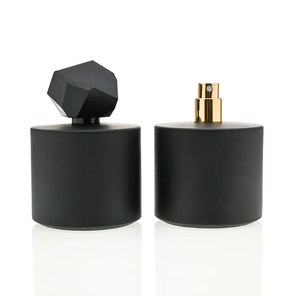 HUA0039 perfume bottle, heavy-base solid high-gloss opaque black cylindrical round glass bottle featuring a prominent asymmetrical multi-faceted polyhedral plastic cap with a smooth high-gloss shiny finish, modern dramatic fragrance packaging design available in 30ml, 50ml, and 100ml