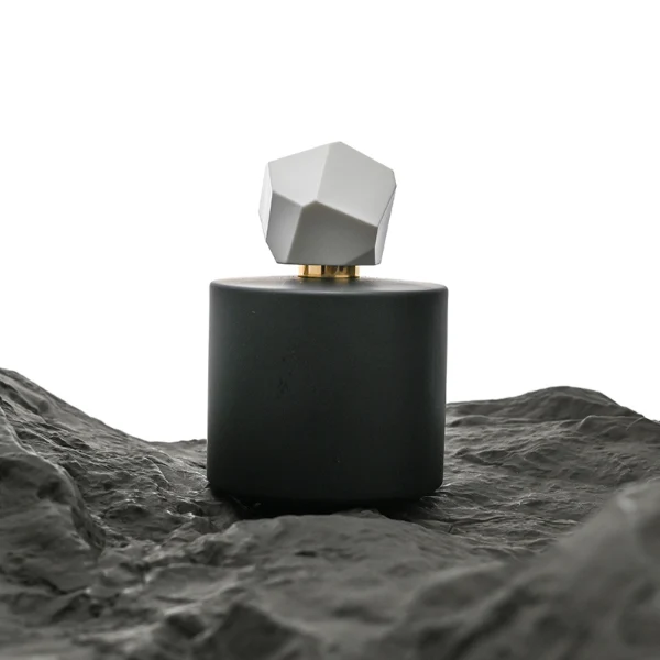 HUA0039 perfume bottle, heavy-base solid high-gloss opaque black cylindrical round glass bottle featuring a prominent asymmetrical multi-faceted polyhedral plastic cap with a smooth high-gloss shiny finish, modern dramatic fragrance packaging design available in 30ml, 50ml, and 100ml