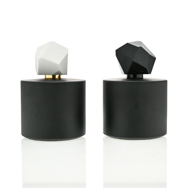 HUA0039 perfume bottle, heavy-base solid high-gloss opaque black cylindrical round glass bottle featuring a prominent asymmetrical multi-faceted polyhedral plastic cap with a smooth high-gloss shiny finish, modern dramatic fragrance packaging design available in 30ml, 50ml, and 100ml