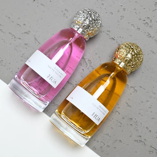 HUA0057 perfume bottle with clear oval glass body, gold or silver decorative textured spherical cap, 100 ml capacity, modern luxury fragrance packaging design.