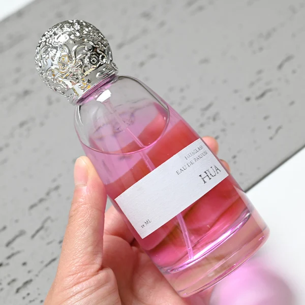 HUA0057 perfume bottle with clear oval glass body, gold or silver decorative textured spherical cap, 100 ml capacity, modern luxury fragrance packaging design.