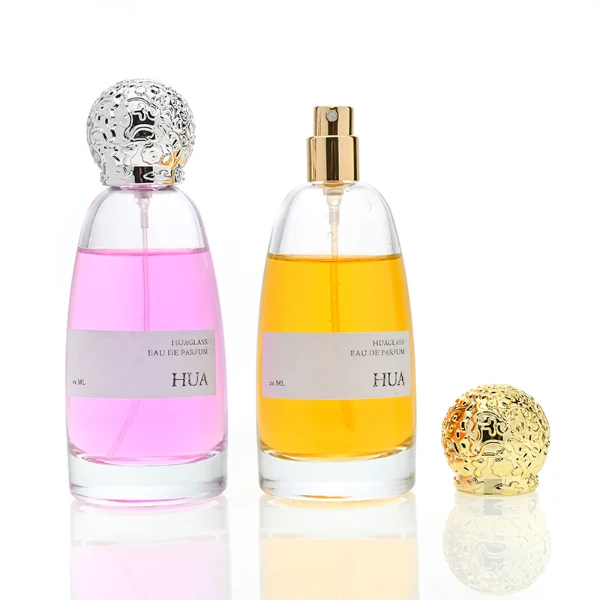 HUA0057 perfume bottle with clear oval glass body, gold or silver decorative textured spherical cap, 100 ml capacity, modern luxury fragrance packaging design.