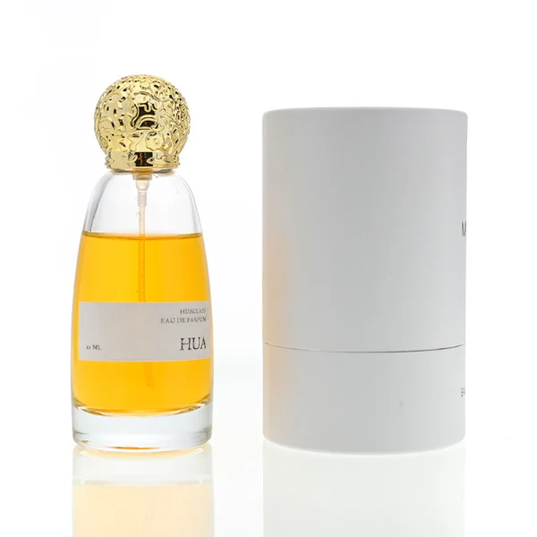 HUA0057 perfume bottle with clear oval glass body, gold or silver decorative textured spherical cap, 100 ml capacity, modern luxury fragrance packaging design.