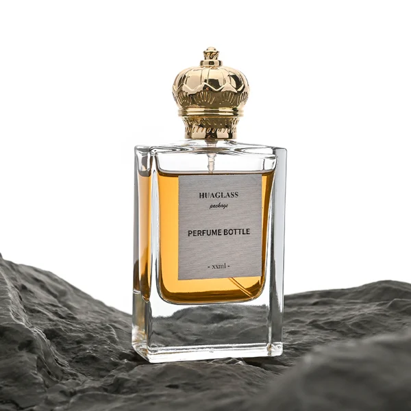 HUA0061 perfume bottle, heavy-base rectangular cuboid glass bottle with clear finish, featuring a square paper label, a matching neck, and an ornate imperial crown-shaped zinc alloy cap with a smooth polished gold finish, elegant modern fragrance packaging design available in 30ml and 50ml