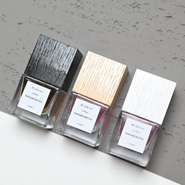 HUA0007 perfume bottle, luxury heavy-base square cuboid glass bottle with high-transparency clear finish, featuring a square paper label and a prominent tall flush-fit square natural textured wooden cap showcasing deep vertical wood grains, minimalist elegant fragrance packaging design available in 30ml, 50ml, and 100ml