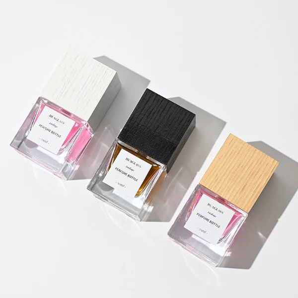HUA0007 perfume bottle, luxury heavy-base square cuboid glass bottle with high-transparency clear finish, featuring a square paper label and a prominent tall flush-fit square natural textured wooden cap showcasing deep vertical wood grains, minimalist elegant fragrance packaging design available in 30ml, 50ml, and 100ml