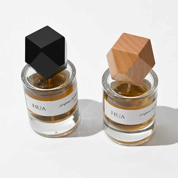 HUA0053 perfume bottle, heavy-base cylindrical round glass bottle with clear finish, featuring a wide wrapped paper label, a gold collar neck accent, and a unique polyhedral faceted diamond-shaped wood cap with subtle grain textures, elegant modern fragrance packaging design available in 30ml, 50ml, and 100ml
