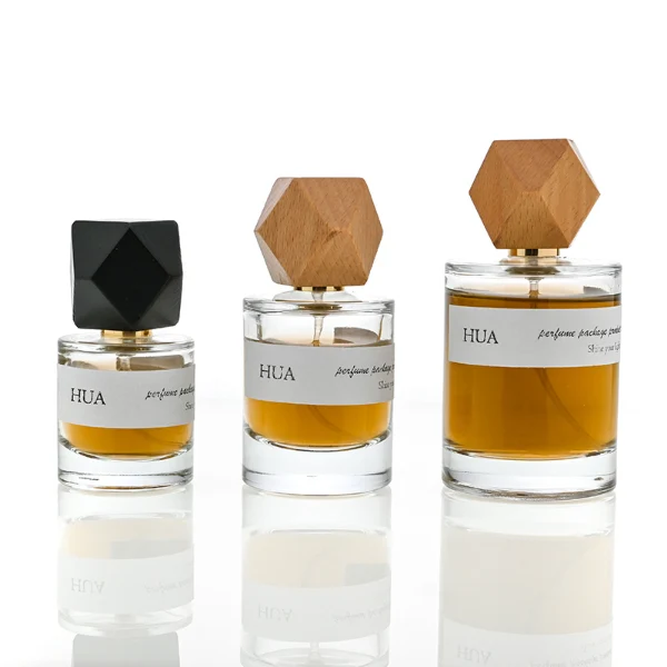 HUA0053 perfume bottle, heavy-base cylindrical round glass bottle with clear finish, featuring a wide wrapped paper label, a gold collar neck accent, and a unique polyhedral faceted diamond-shaped wood cap with subtle grain textures, elegant modern fragrance packaging design available in 30ml, 50ml, and 100ml
