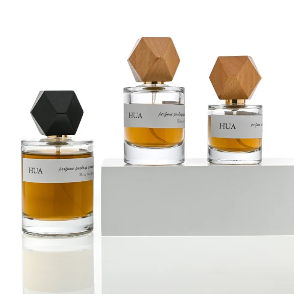 HUA0053 perfume bottle, heavy-base cylindrical round glass bottle with clear finish, featuring a wide wrapped paper label, a gold collar neck accent, and a unique polyhedral faceted diamond-shaped wood cap with subtle grain textures, elegant modern fragrance packaging design available in 30ml, 50ml, and 100ml