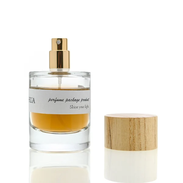 HUA0035 perfume bottle, heavy-base cylindrical round glass bottle with clear finish, featuring a horizontal paper label, a polished gold neck, and a wide cylindrical timber cap with a natural smooth grain finish, elegant modern fragrance packaging design available in 30ml, 50ml, and 100ml