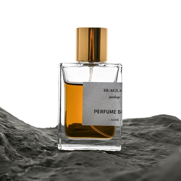 HUA0049 perfume bottle, heavy-base rectangular cuboid glass bottle with clear finish, featuring a corner-wrapped square paper label, a coordinating collar neck accent, and a tall cylindrical aluminum cap with a smooth polished metallic finish, elegant modern fragrance packaging design available in 30ml, 50ml, and 100ml