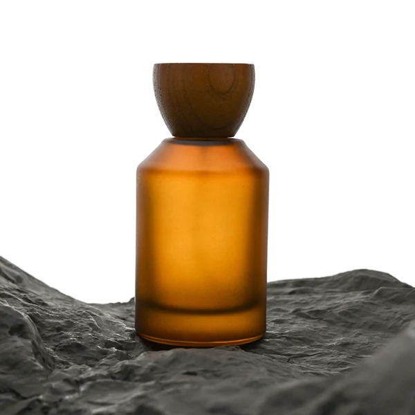 HUA0050 perfume bottle, cylindrical round glass bottle with multi-angled sloping beveled shoulders in solid high-gloss opaque black, clear amber, or frosted amber finish, featuring an eye-catching inverted conical cup-shaped wood cap with prominent natural wood grain lines, modern fragrance packaging design available in 30ml, 50ml, and 100ml