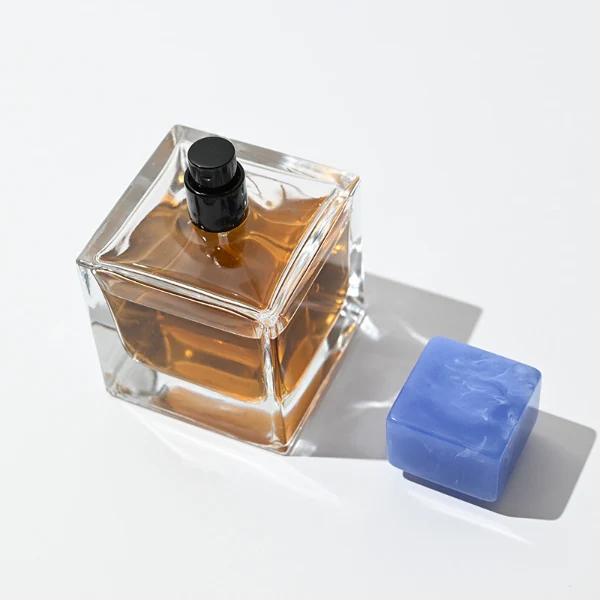 HUA0030 perfume bottle, heavy-base rectangular cuboid glass bottle with clear finish, featuring a matching neck, and a low-profile cylindrical resin cap with a colorful marbled finish, elegant modern fragrance packaging design available in 30ml, 50ml, and 100ml