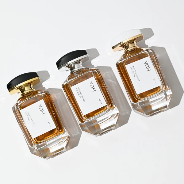 HUA0013 perfume bottle, heavy-base octagonal faceted glass bottle with clear finish, featuring a square paper label, a matching neck, and an arched rectangular plastic cap with a smooth high-gloss shiny finish, elegant modern fragrance packaging design available in 30ml, 50ml, and 100ml