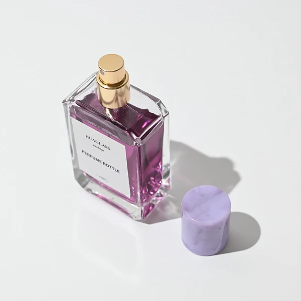 HUA0048 perfume bottle, heavy-base clear glass bottle with octagonal chamfered corners, featuring a square paper label and a tall cylindrical resin cap with an eye-catching marbled texture, elegant modern fragrance packaging design available in 30ml, 50ml, and 100ml