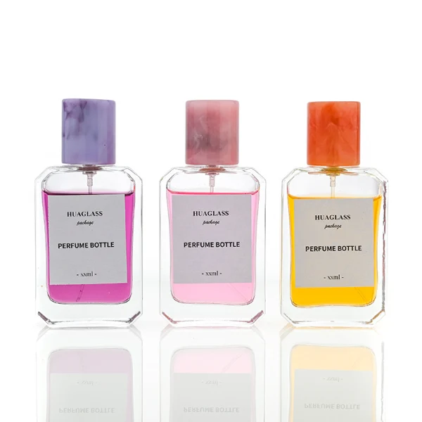 HUA0048 perfume bottle, heavy-base clear glass bottle with octagonal chamfered corners, featuring a square paper label and a tall cylindrical resin cap with an eye-catching marbled texture, elegant modern fragrance packaging design available in 30ml, 50ml, and 100ml