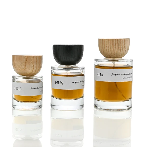 HUA0032 perfume bottle, heavy-base cylindrical round glass bottle with clear finish, featuring a horizontal paper label, a matching neck, and an inverted conical timber cap with a natural smooth grain finish, elegant modern fragrance packaging design available in 30ml, 50ml, and 100ml