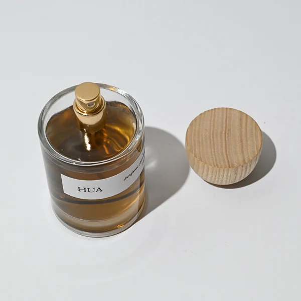 HUA0032 perfume bottle, heavy-base cylindrical round glass bottle with clear finish, featuring a horizontal paper label, a matching neck, and an inverted conical timber cap with a natural smooth grain finish, elegant modern fragrance packaging design available in 30ml, 50ml, and 100ml
