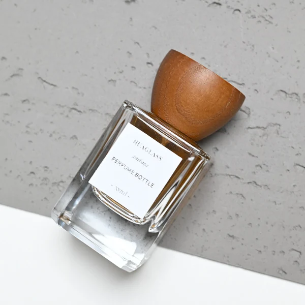 HUA0002 perfume bottle, heavy-base rectangular cuboid glass bottle with clear finish, featuring a square paper label, a matching neck, and an inverted conical timber cap with a natural grain finish, elegant modern fragrance packaging design available in 30ml, 50ml, and 100ml