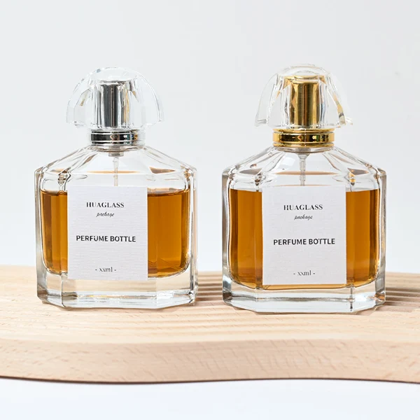 HUA0011 perfume bottle, luxury heavy-base polyhedral faceted glass bottle with high-transparency clear finish, featuring a square paper label and a brilliant multi-faceted crystalline acrylic plastic crown cap with a metallic inner core, elegant classic fragrance packaging design in 100ml