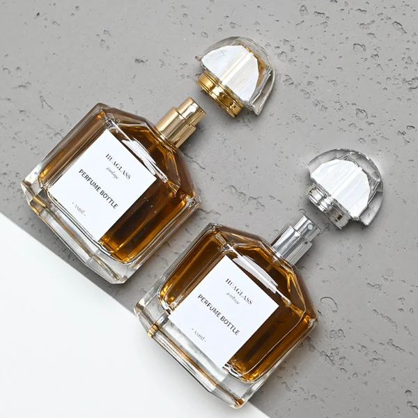 HUA0011 perfume bottle, luxury heavy-base polyhedral faceted glass bottle with high-transparency clear finish, featuring a square paper label and a brilliant multi-faceted crystalline acrylic plastic crown cap with a metallic inner core, elegant classic fragrance packaging design in 100ml