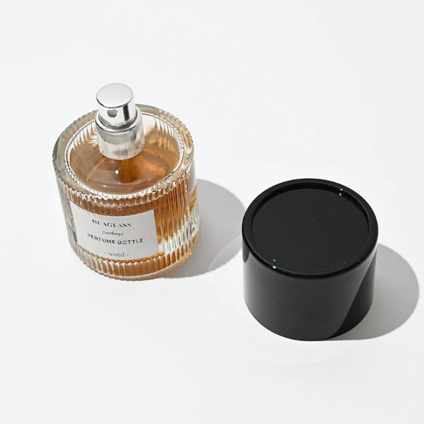 HUA0010 perfume bottle, heavy-base vertically ribbed cylindrical round glass bottle with clear finish, featuring a square paper label, a matching neck, and a tall cylindrical plastic cap with a smooth high-gloss shiny finish, elegant modern fragrance packaging design available in 40ml