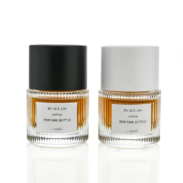 HUA0010 perfume bottle, heavy-base vertically ribbed cylindrical round glass bottle with clear finish, featuring a square paper label, a matching neck, and a tall cylindrical plastic cap with a smooth high-gloss shiny finish, elegant modern fragrance packaging design available in 40ml