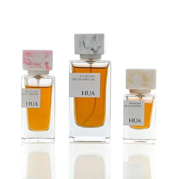 HUA0040 perfume bottle, heavy-base rectangular cuboid glass bottle with clear finish, featuring a side-aligned square paper label and a short rectangular block-shaped resin cap with an eye-catching marbled texture, elegant modern fragrance packaging design available in 15ml, 30ml, 50ml, and 100ml