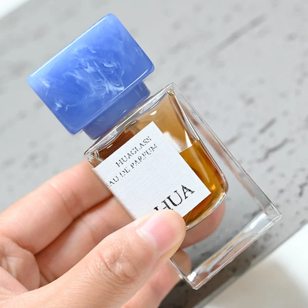 HUA0040 perfume bottle, heavy-base rectangular cuboid glass bottle with clear finish, featuring a side-aligned square paper label and a short rectangular block-shaped resin cap with an eye-catching marbled texture, elegant modern fragrance packaging design available in 15ml, 30ml, 50ml, and 100ml