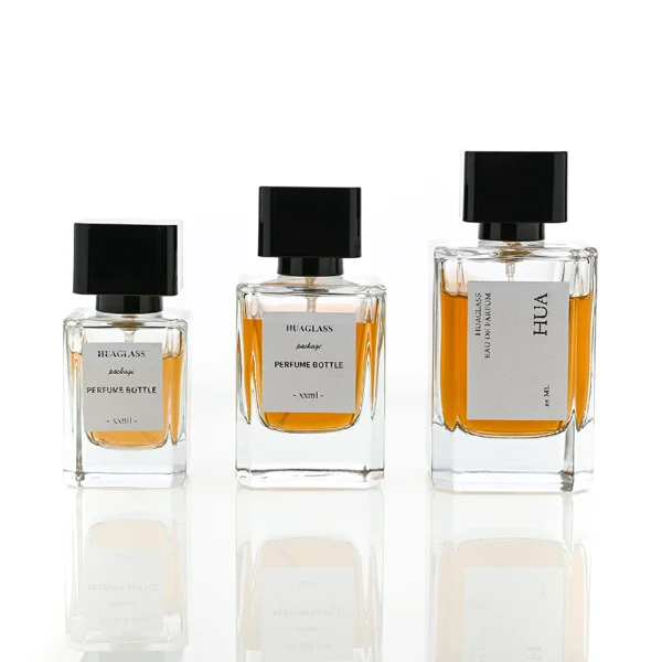 HUA0051 perfume bottle, heavy-base rectangular cuboid glass bottle with clear finish, featuring a square paper label, a black collar neck accent, and a short rectangular block-shaped solid black plastic cap with a smooth high-gloss shiny finish, elegant modern fragrance packaging design available in 30ml, 50ml, and 100ml