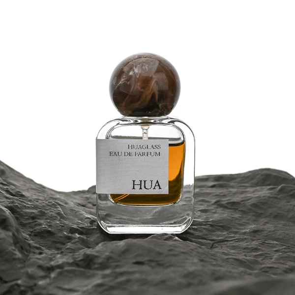 HUA0042 perfume bottle, clear flattened oval flask glass bottle featuring a prominent spherical ball-shaped resin cap with an eye-catching marbled texture and organic fluid swirls, modern playful fragrance packaging design available in 30ml, 50ml, and 100ml