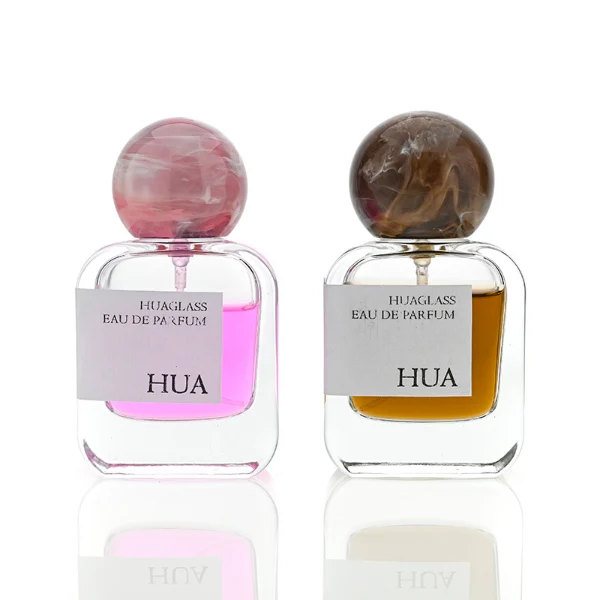 HUA0042 perfume bottle, clear flattened oval flask glass bottle featuring a prominent spherical ball-shaped resin cap with an eye-catching marbled texture and organic fluid swirls, modern playful fragrance packaging design available in 30ml, 50ml, and 100ml